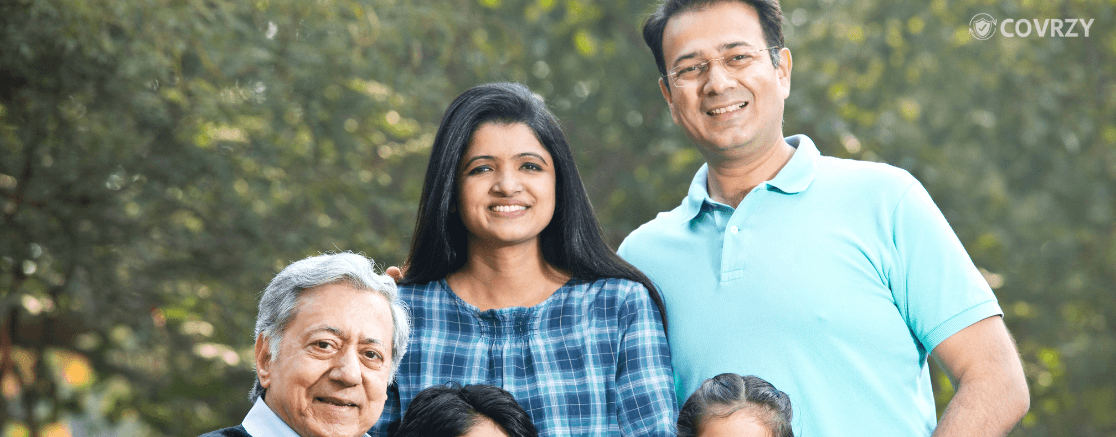 An Indian family of four, consisting of a father wearing a blue t-shit with his wife, an old man and two children